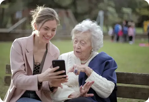 Mujer enseñando teléfono a persona mayor